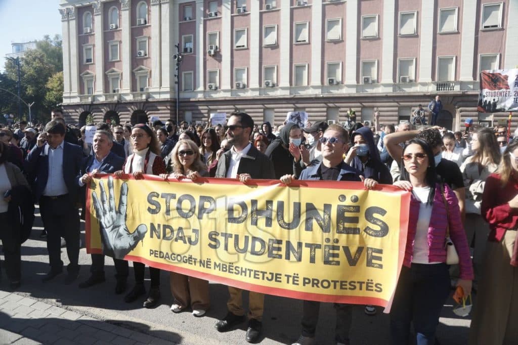 Pedagogë mbajnë banderolën "Stop dhunës ndaj studentëve – Pedagogët në mbështetje të protestës" gjatë marshimit në Tiranë